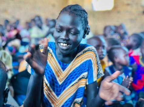 A young child clapping in a classroom