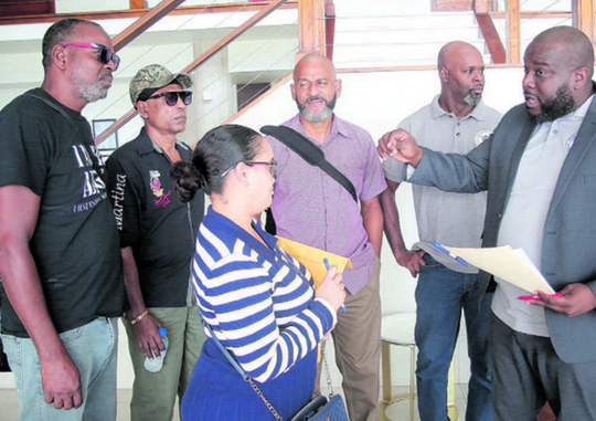 President of the Steel Workers’ Union Timothy Bailey, right, speaks to former workers of the ArcelorMittal steel plant after a meeting at Cara Suites in Claxton Bay on Wednesday.PHOTO BY RISHI RAGOONATH