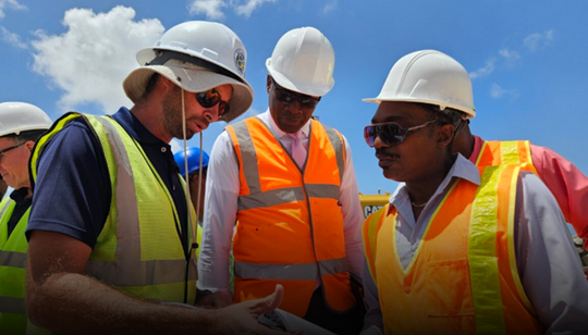Minister of Environment Adrian Forde (right) and PS David Leacock (centre) looking at project plans from General Manager of C.O Williams Marc Atwell (left).