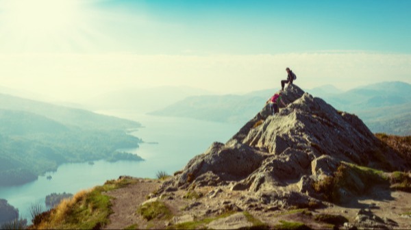 Two hikers on top of a mountain enjoying the view