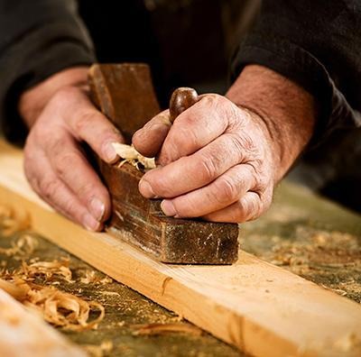 Person sanding lumber by hand with a hand sander block