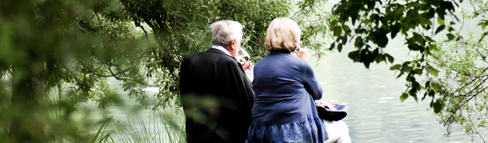 retired couple sitting next to a pond