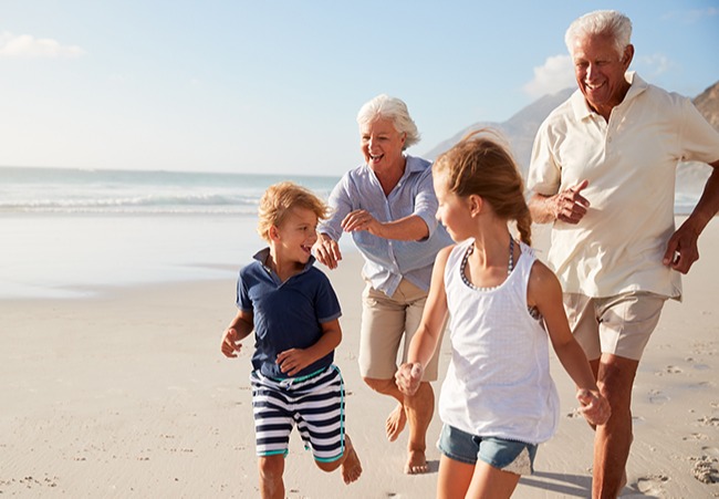 Grandparents running on beach with grandkids.