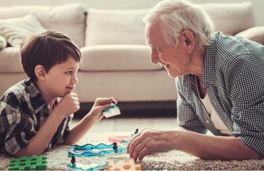 Grandfather and grandchild playing with toys on floor
