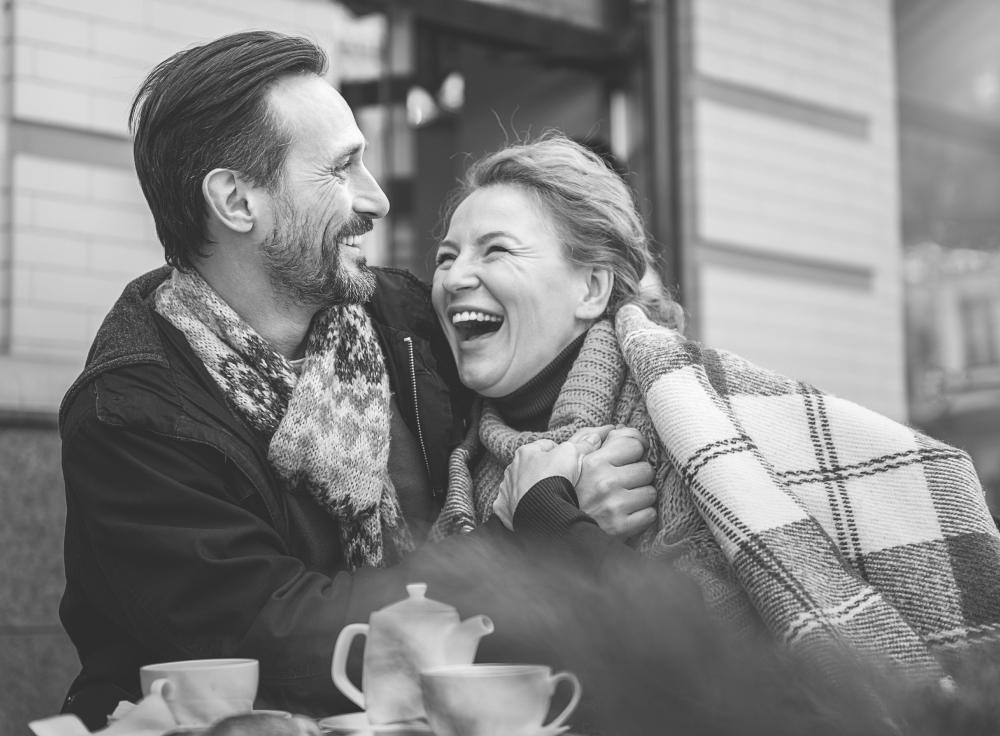 Photo of a couple sitting down and holding hands with a joyful look on their faces