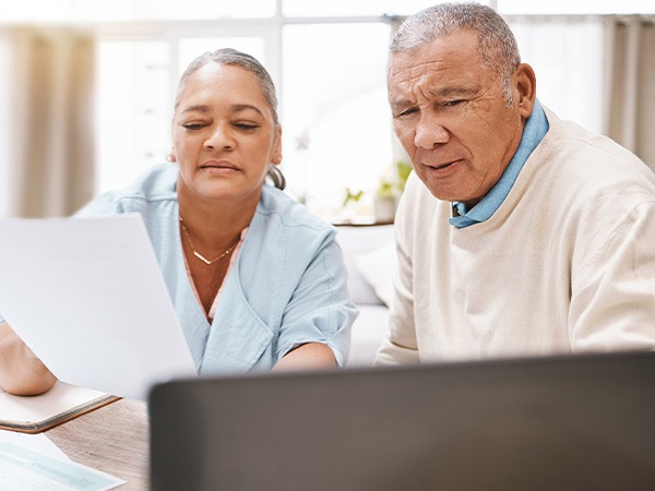 older-couple-looking-at-computer-and-papers