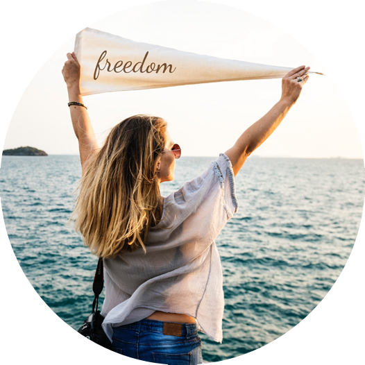 woman wearing sunglasses looking out at the water holding a banner that says freedom