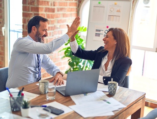 Man and women celebrating in an investment management office 