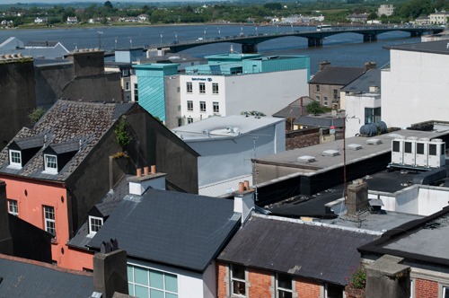 urban rooftops next to a bridge stretching over a body of water