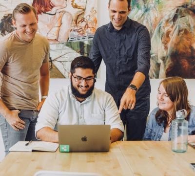 people in a meeting looking over at a laptop and smiling