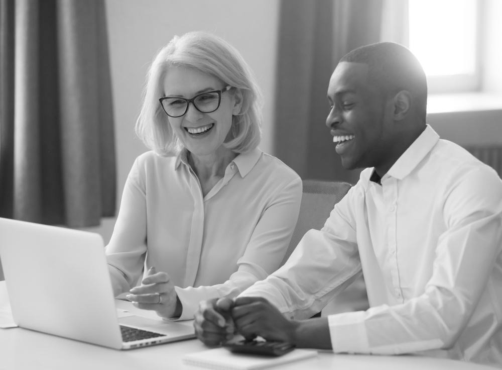 Photo of a man and woman smiling while looking at a laptop screen