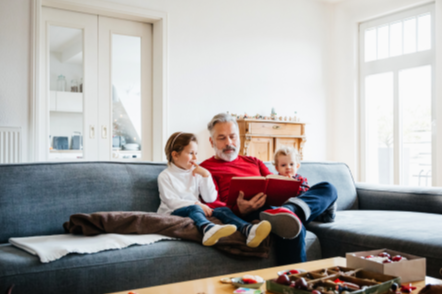 man reading to two children on a couch