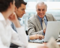 Three business people at a meeting looking at a laptop