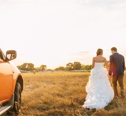 Married couple walking through a field at sunset, noting their recent milestone 
