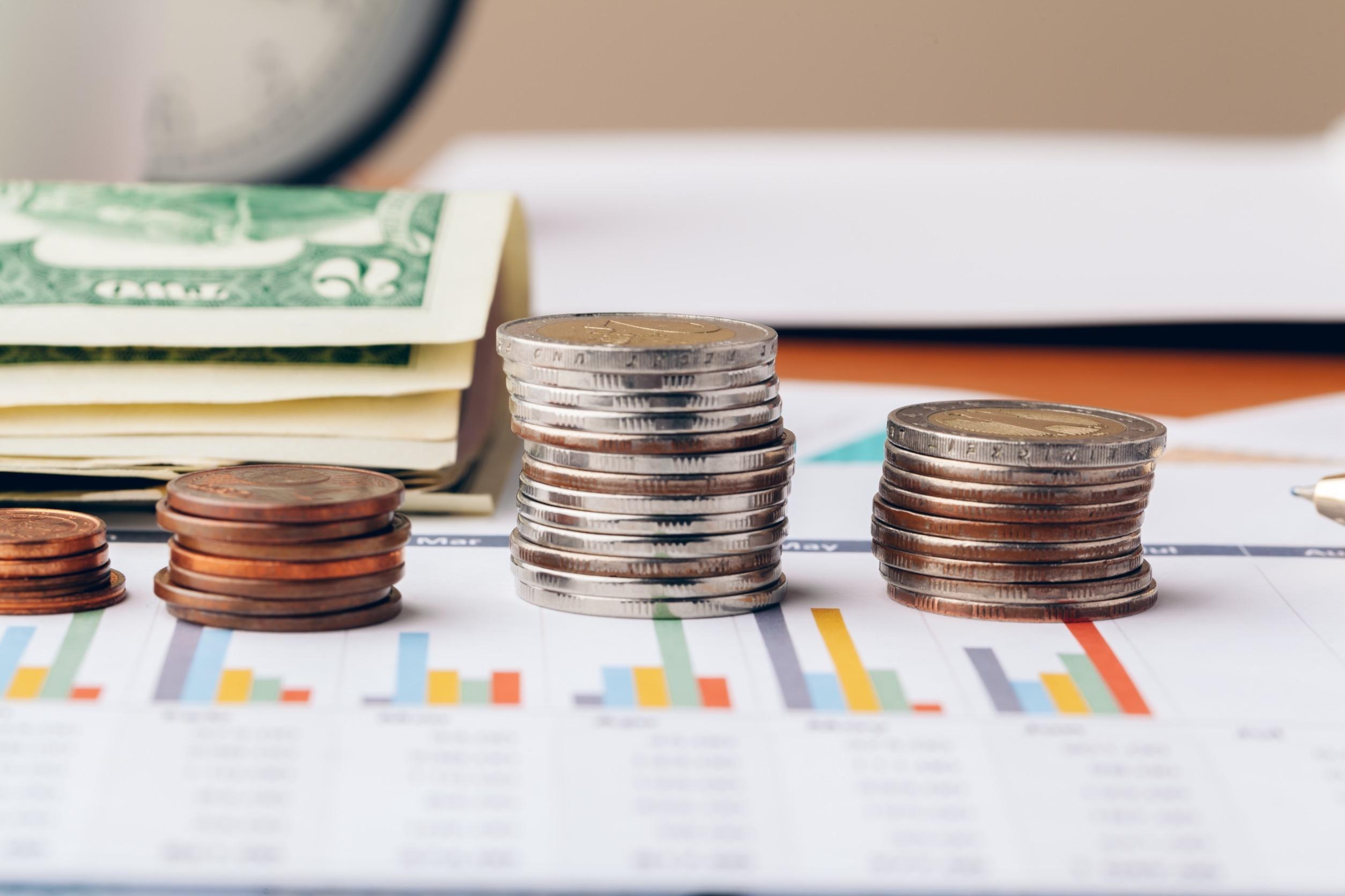 coins and dollar bills stacked on a printed graph