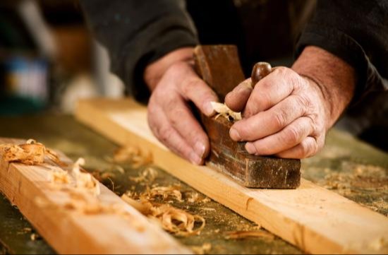 Carpenter using tools to smooth and level wood