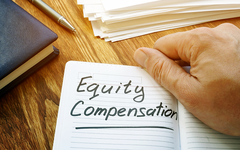 Notebook held open on a desk - Equity Compensation