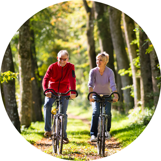 older couple riding bicycles on a trail in the woods