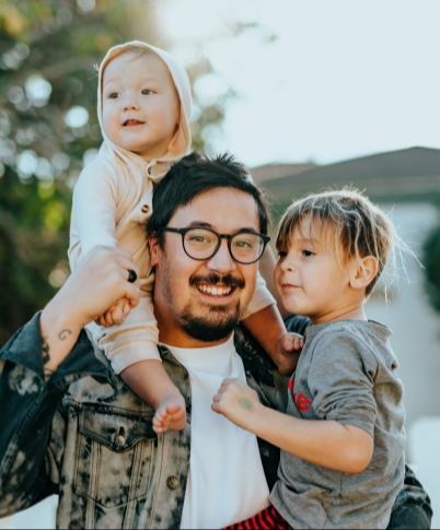 Father smiling and carrying his children.