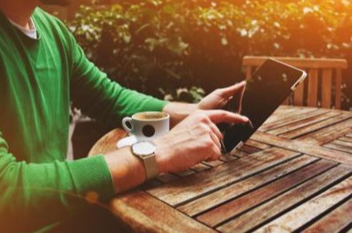 Man holding a tablet with a cup of coffee