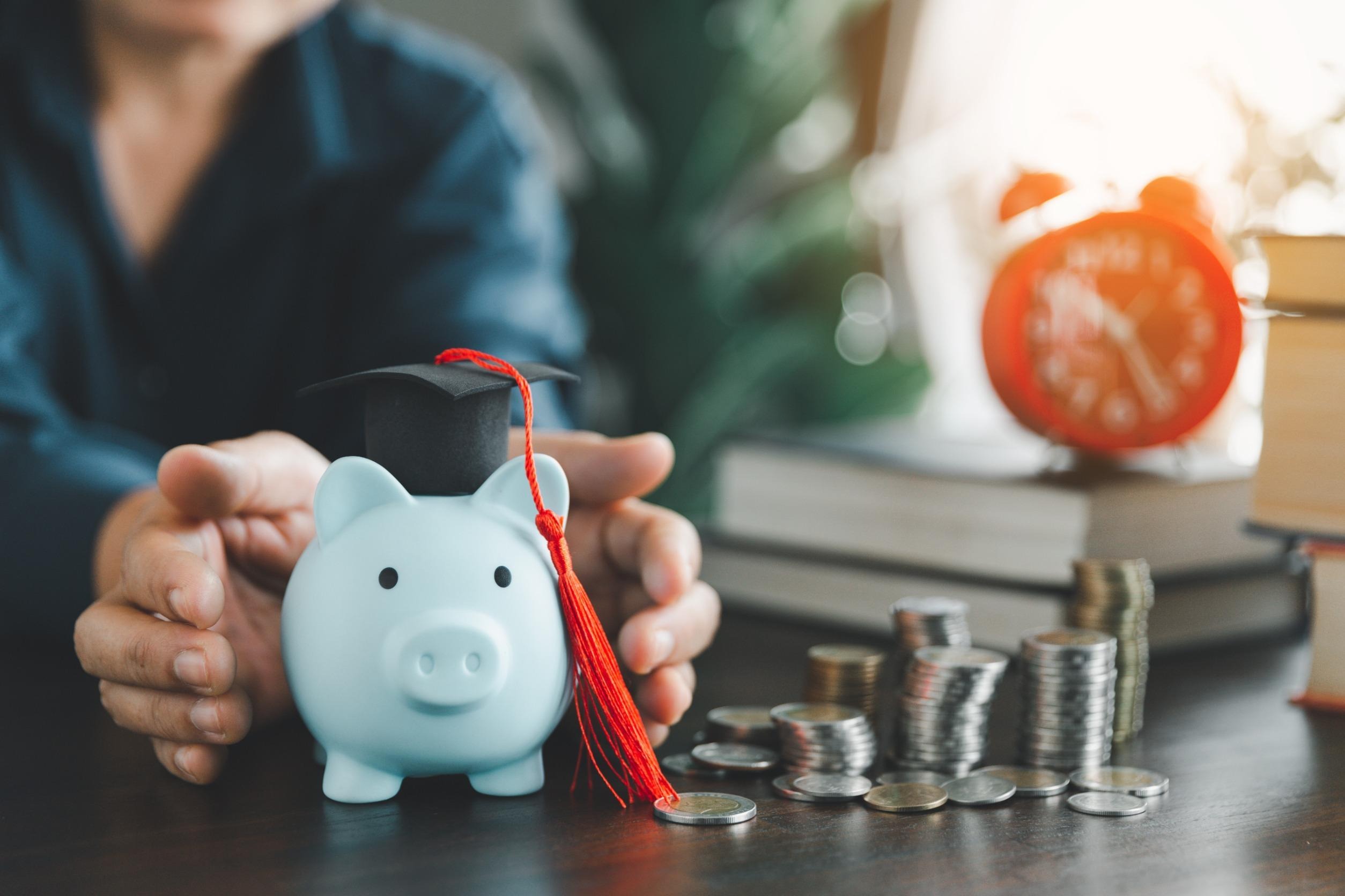 piggy bank with a graduation cap on with stacks of sliver coins next to it