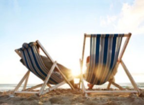 two people sitting in beach chairs on the beach watching the sunset