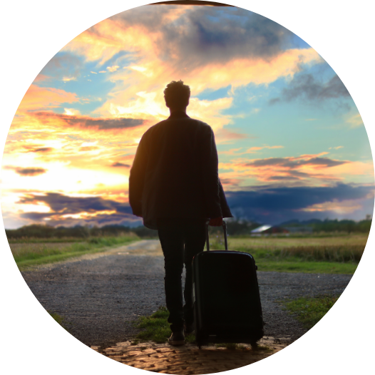 man with suitcase walking into sunset