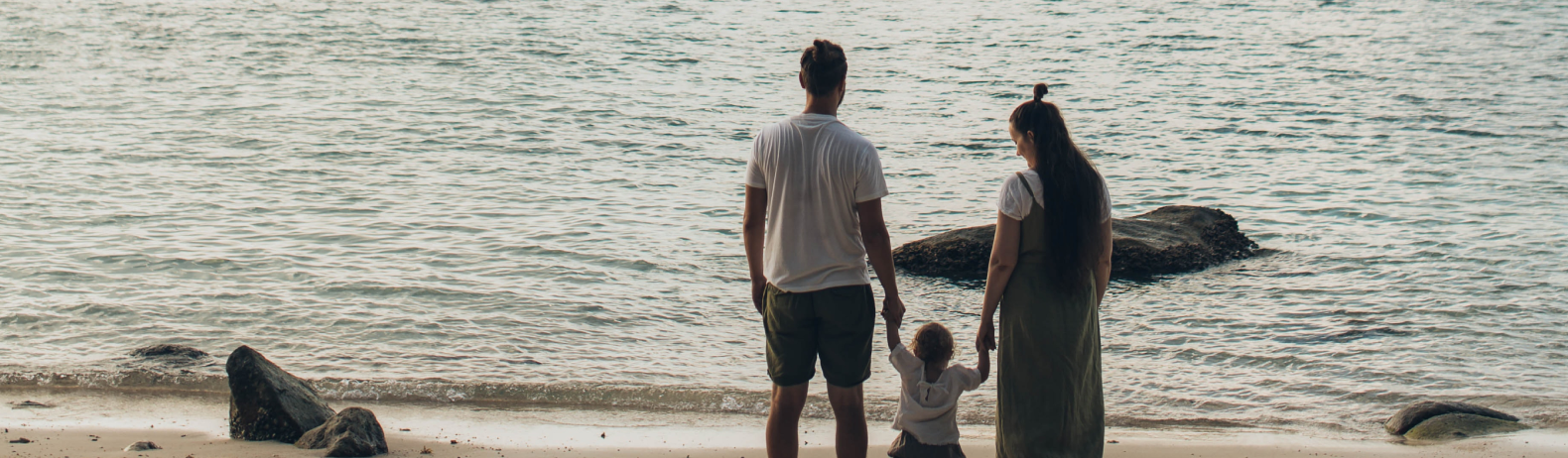parents and young child looking at the ocean