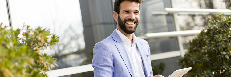 happy man in a light blue suit looking at a tablet