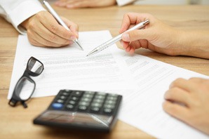 Business professionals signing documents with pen and calculator.