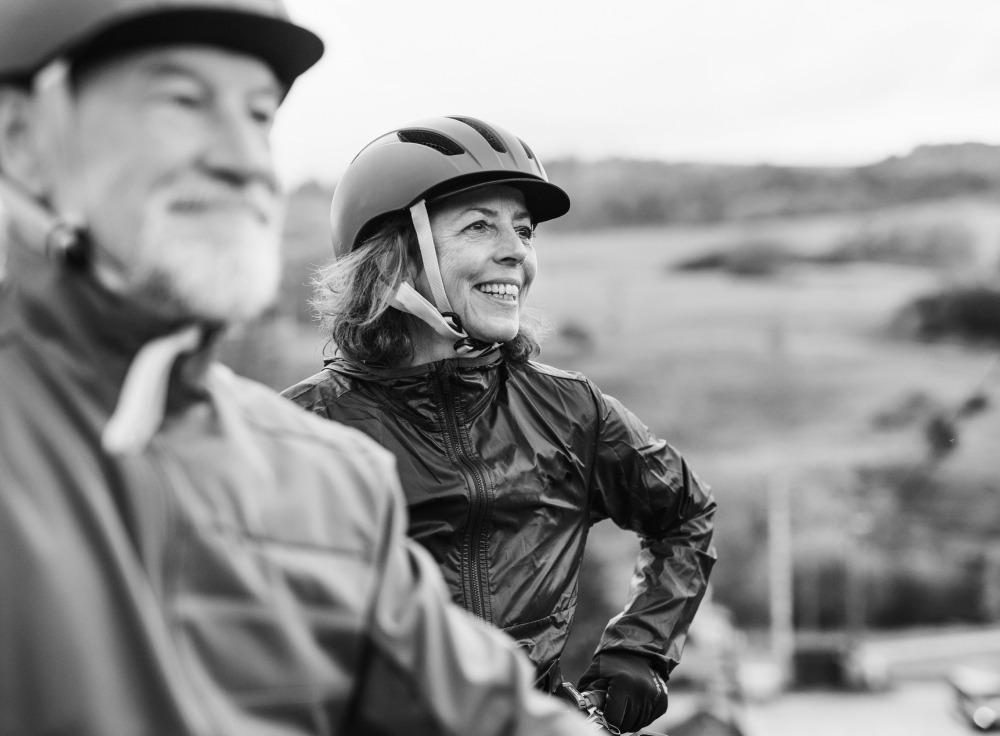 Photo of a man and woman wearing bicycle helmets while looking off into the distance
