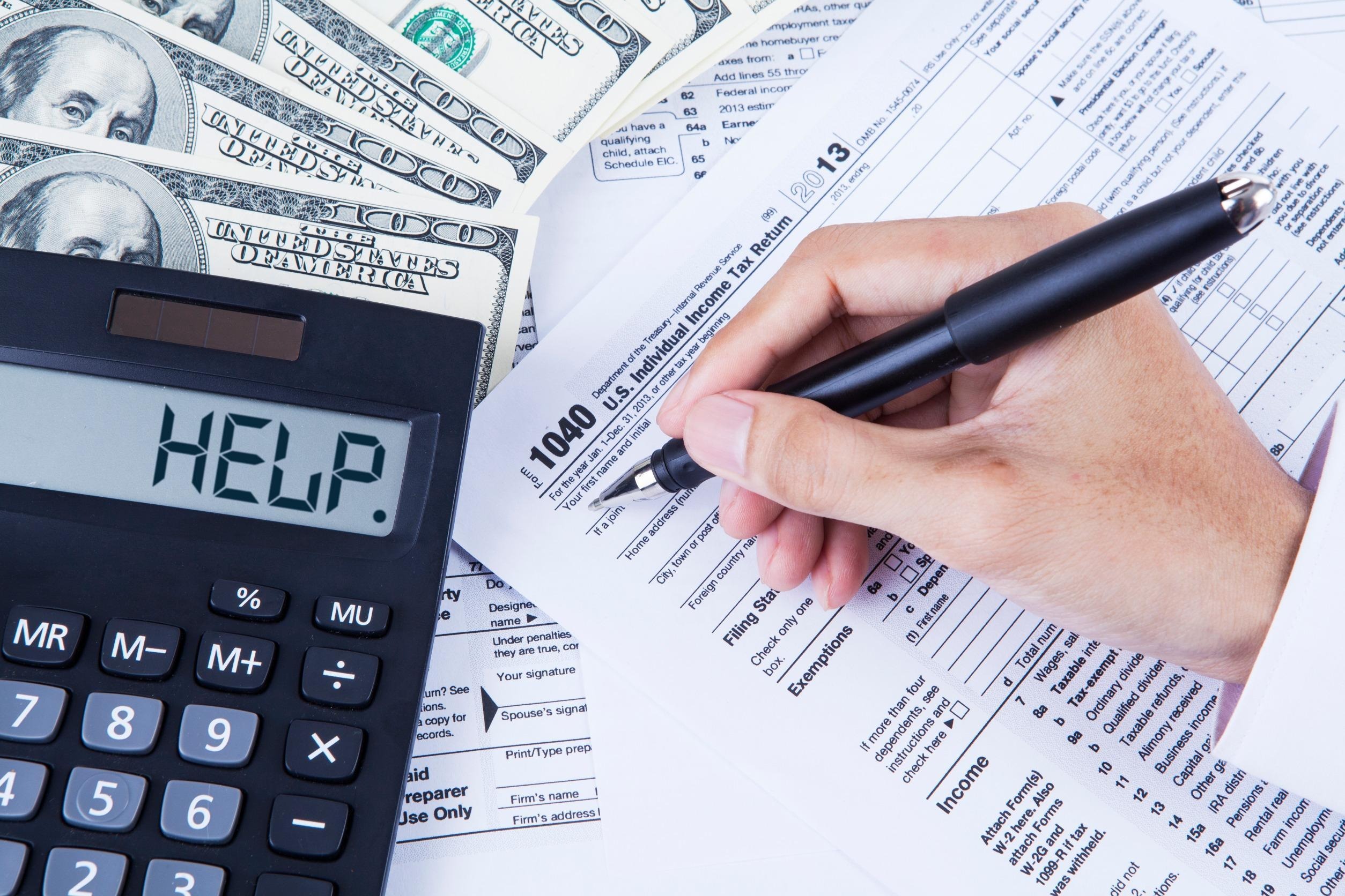 person doing their taxes with a calculator next to them