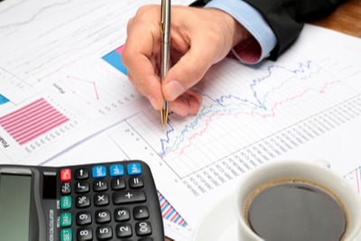 Hand with pen writing on business documents