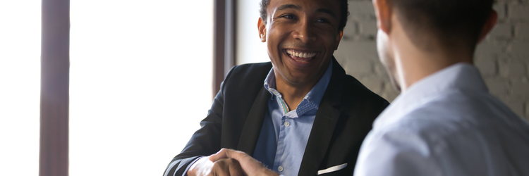 two businessmen shaking hands and smiling