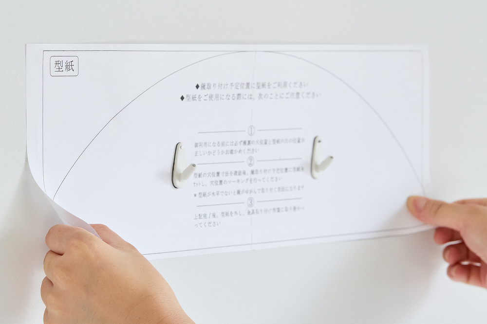 ミラーをつけたい位置を決めたら、付属の「とりつけ用型紙」を壁に合わせて、位置を確認しながら、フックピンを打ち込んでください｜日本のミマツ工芸による佐賀の杉を選び抜いて作った家具『NENRIN（年輪）』｜ウォールミラー・鏡