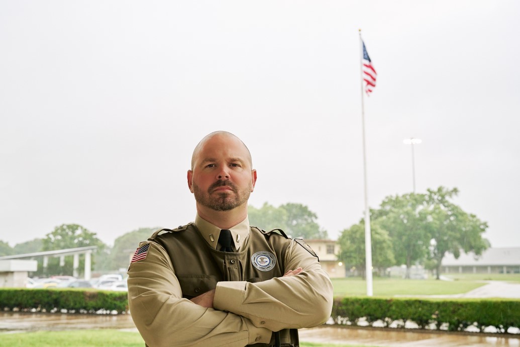 An officer standing with his arms folded, photo credit is the Federal Bureau of Prisons