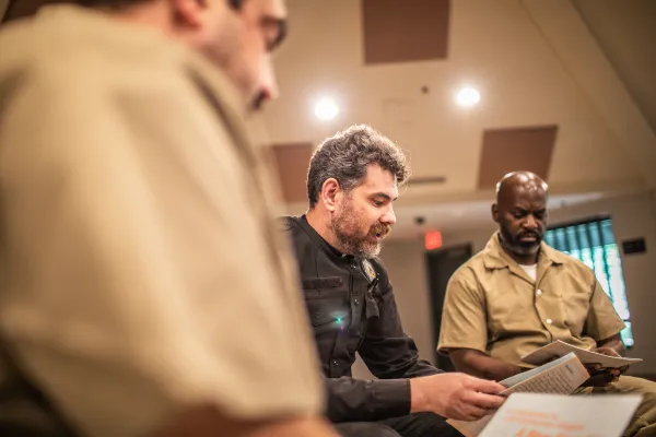 an officer and incarcerated persons reading in a circle