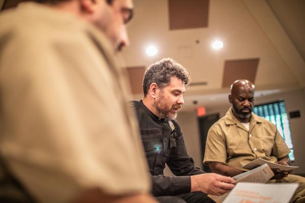 an officer and incarcerated persons reading in a circle