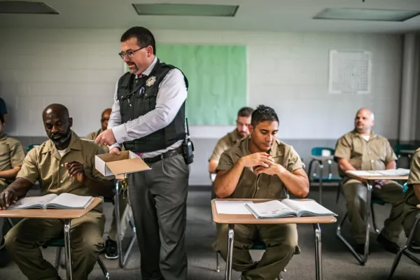 an officer teaching a class of incarcerated persons sitting at school desks