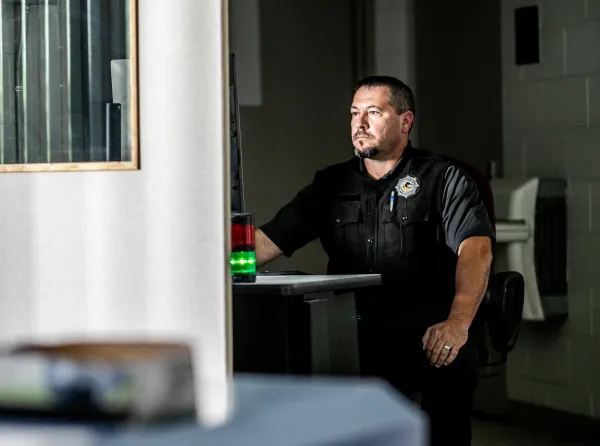 a corrections officer sitting at a computer in a dark room