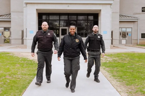 two white male officers one black female officer walking police station