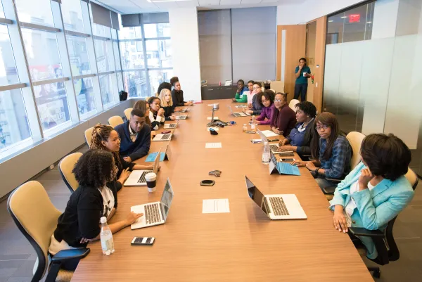 Well-lit conference room with 30 people sitting at the table.