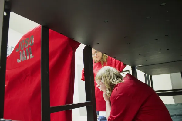 three women talking at their bunk bed in a prison cell