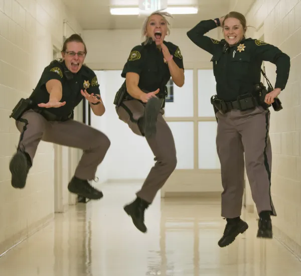three lady sheriffs jumping for joy in the air