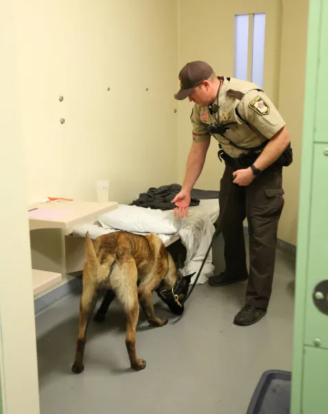 A sheriff and canine search a cell for contraband. Thanks to Scott County Sheriff's Office, Minnesota for the photo