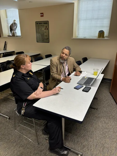 a woman correctional officer talking to a man in a tan suit