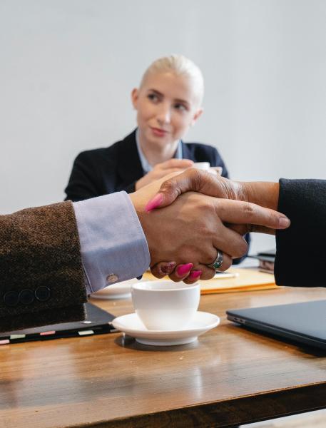 a man and woman shaking hands in front of another woman looking at one of the people