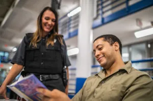 white-female-officer-sharing-book-with-inmate.png