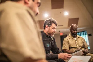 an officer and incarcerated persons reading in a circle