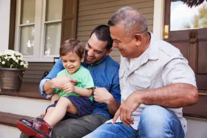 a grandfather, father, and grandson sitting on the porch steps having a laugh